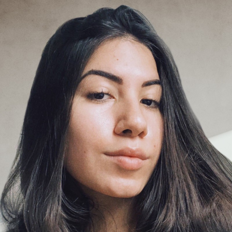 foto da autora branca, de cabelos castanhos escuros e olhos também castanhos escuro na frente de um fundo bege